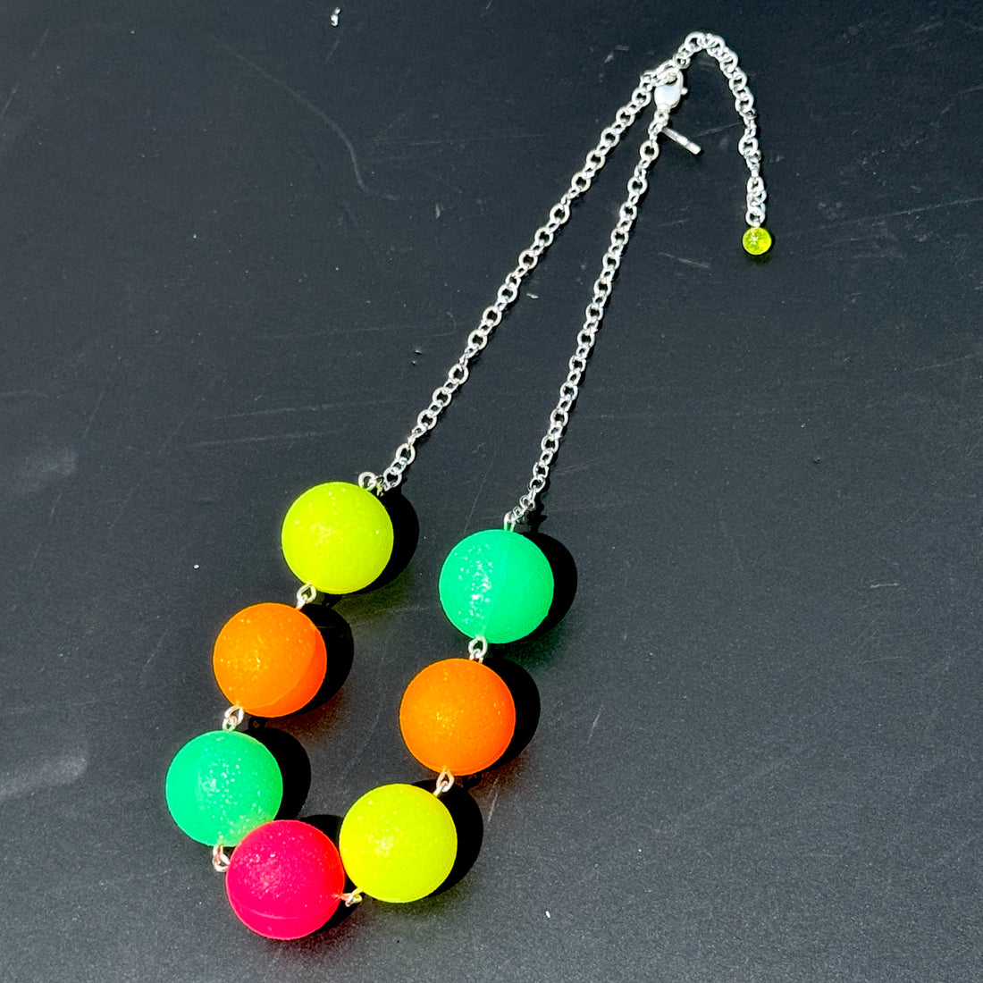 Neon bead necklace on a dark surface