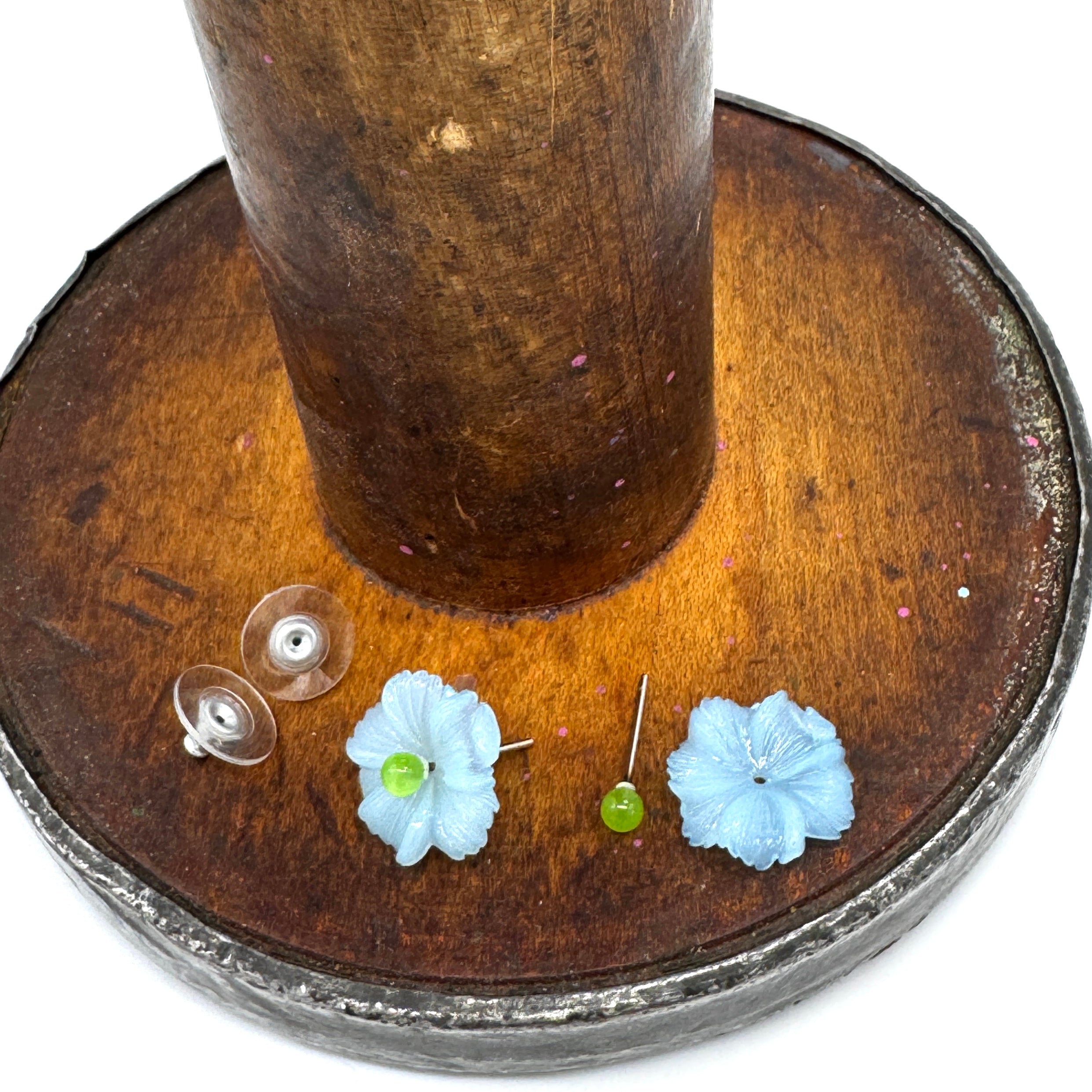 Flower-shaped earrings on a wooden stand