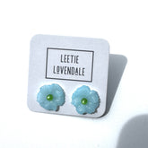 Light blue flower-shaped earrings on a white card with &