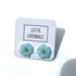 Light blue flower-shaped earrings on a white card with &