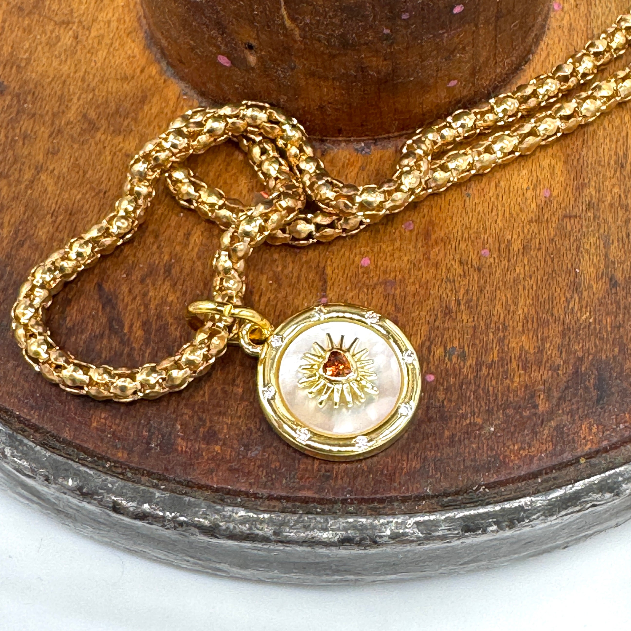 Gold necklace with a decorative pendant on a wooden surface