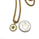Gold necklace with a heart pendant next to a quarter on a white background