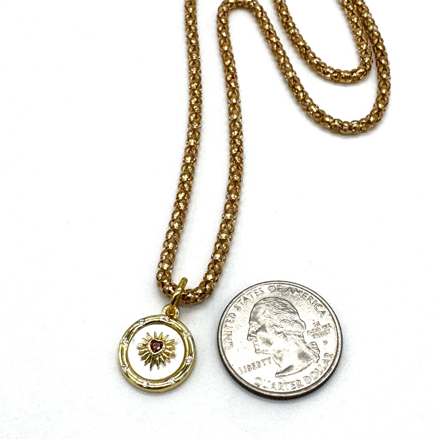 Gold necklace with a pendant and a coin on a white background