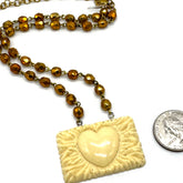 Necklace with a heart-shaped pendant next to a quarter for scale on a white background