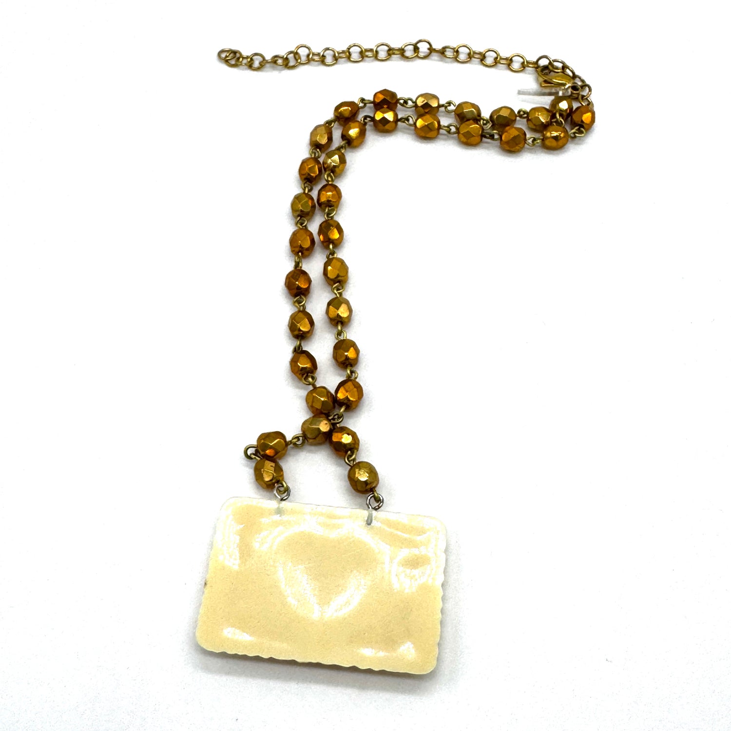 Necklace with brown beaded chain and rectangular white pendant on a white background