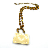 Necklace with brown beaded chain and rectangular white pendant on a white background