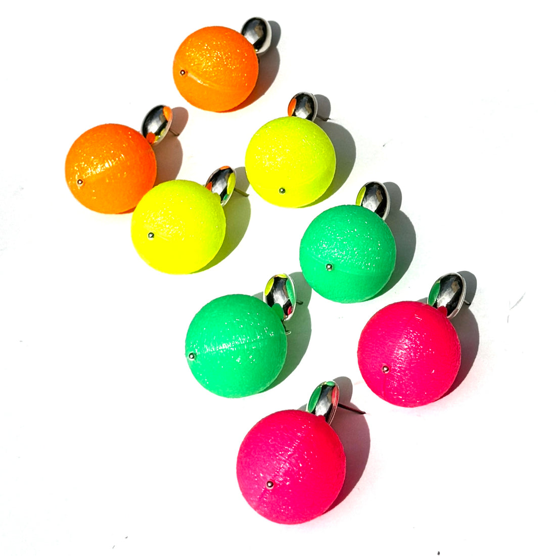 Neon-colored ball earrings with metal hooks on a white background