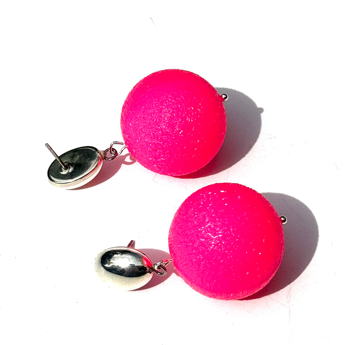 Pink spherical earrings with silver posts on a white background