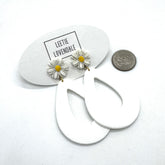 White hoop earrings with daisy flower charms on a white background with &