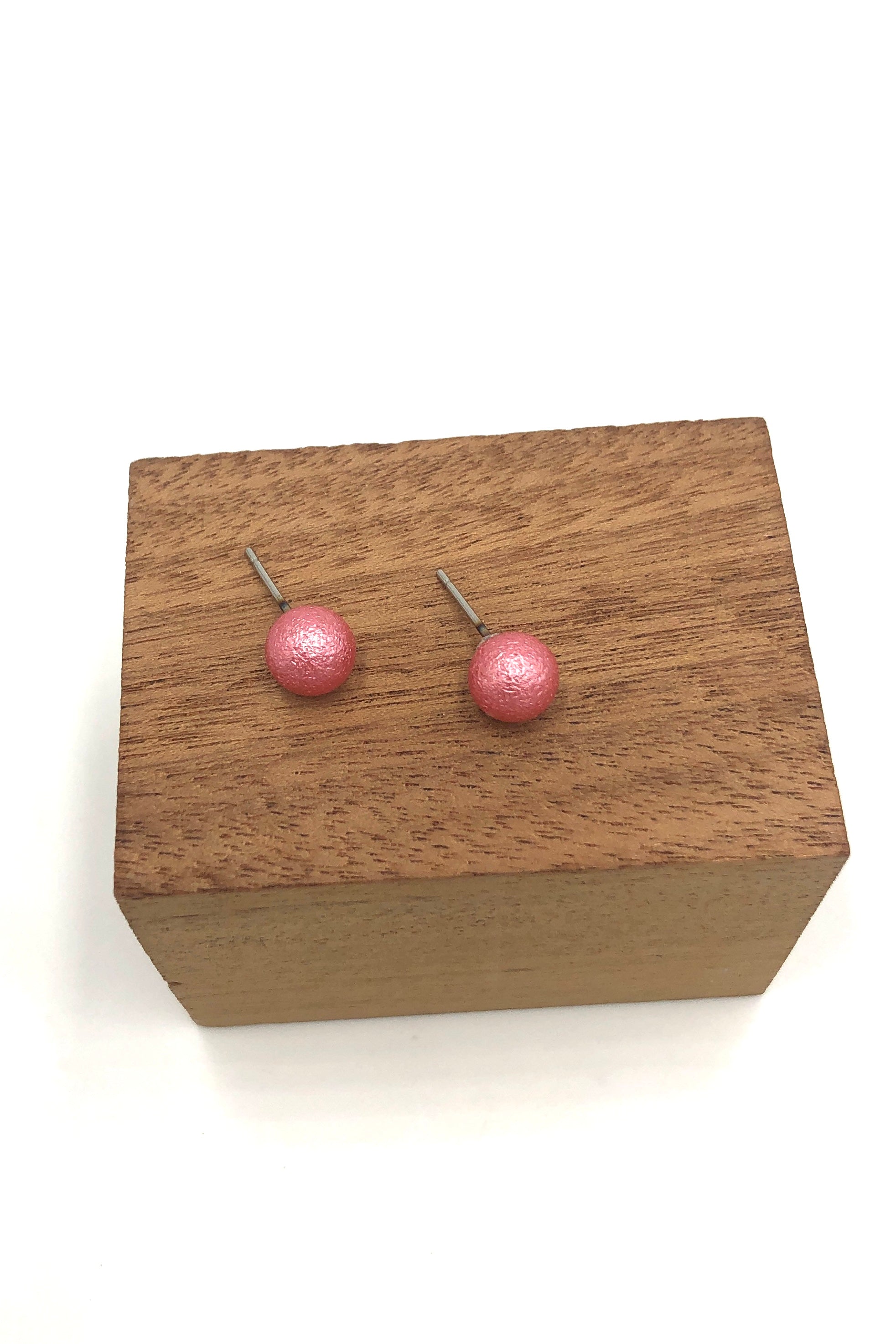 French pink pitted ball stud earrings on wood stand