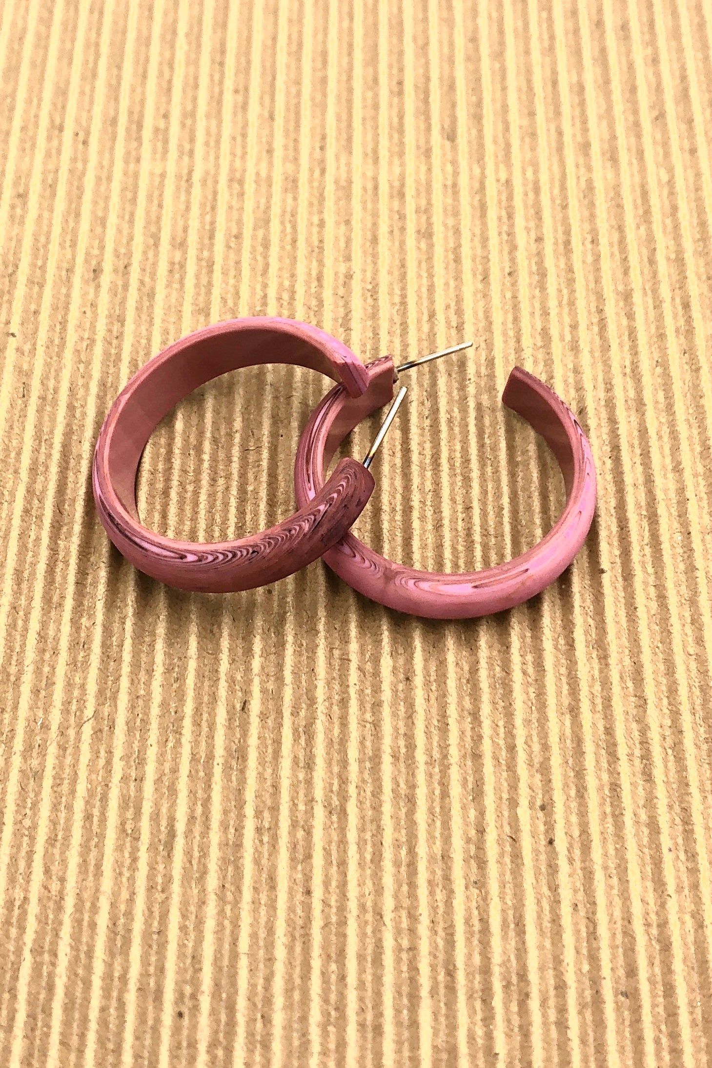 dusty pink marbled hoop earrings on brown background