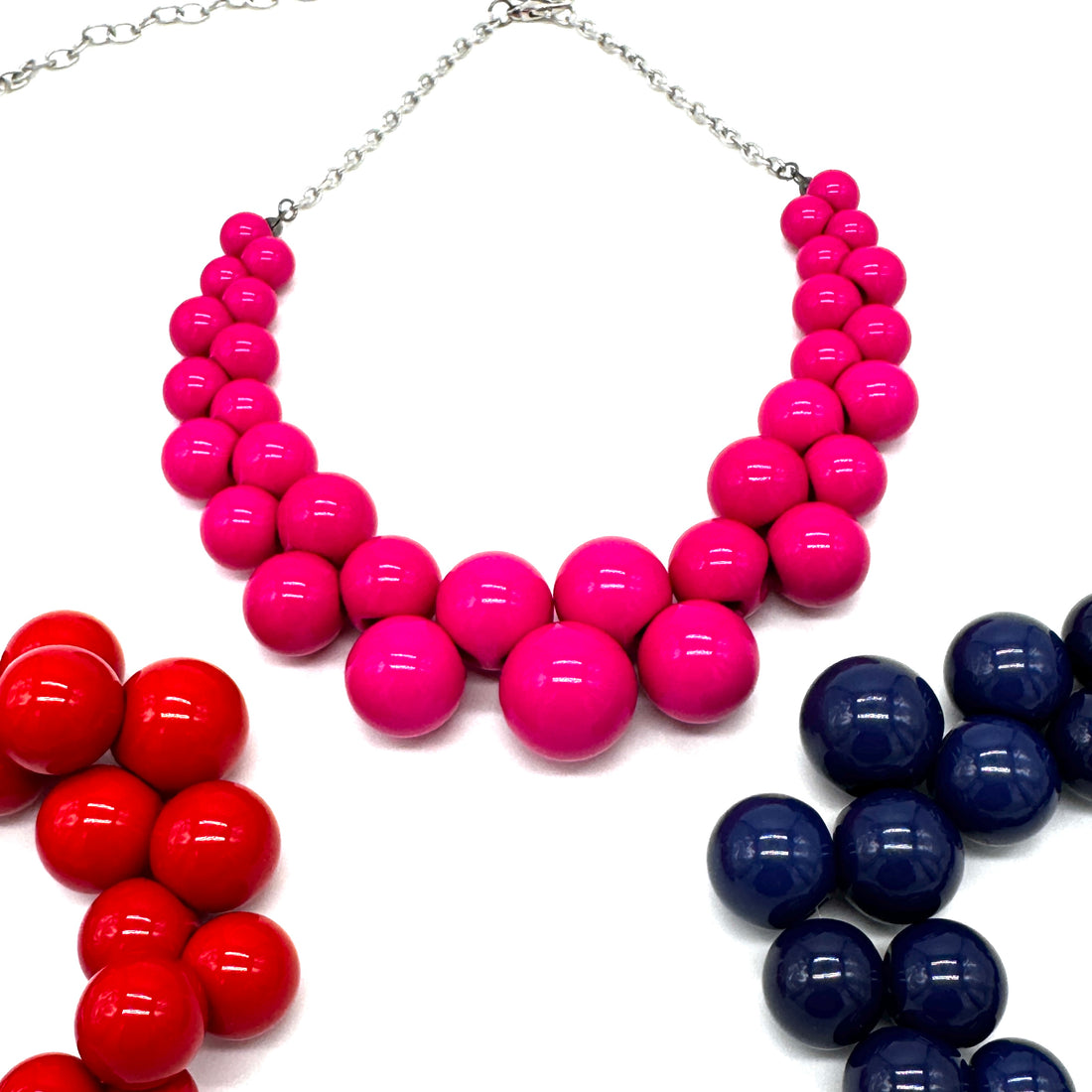 Necklaces with pink, red, and blue bead segments on a white background