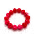 Red beaded bracelet on a white textured surface