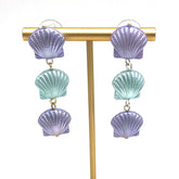Periwinkle and ice blue seashell style earrings on a gold stand