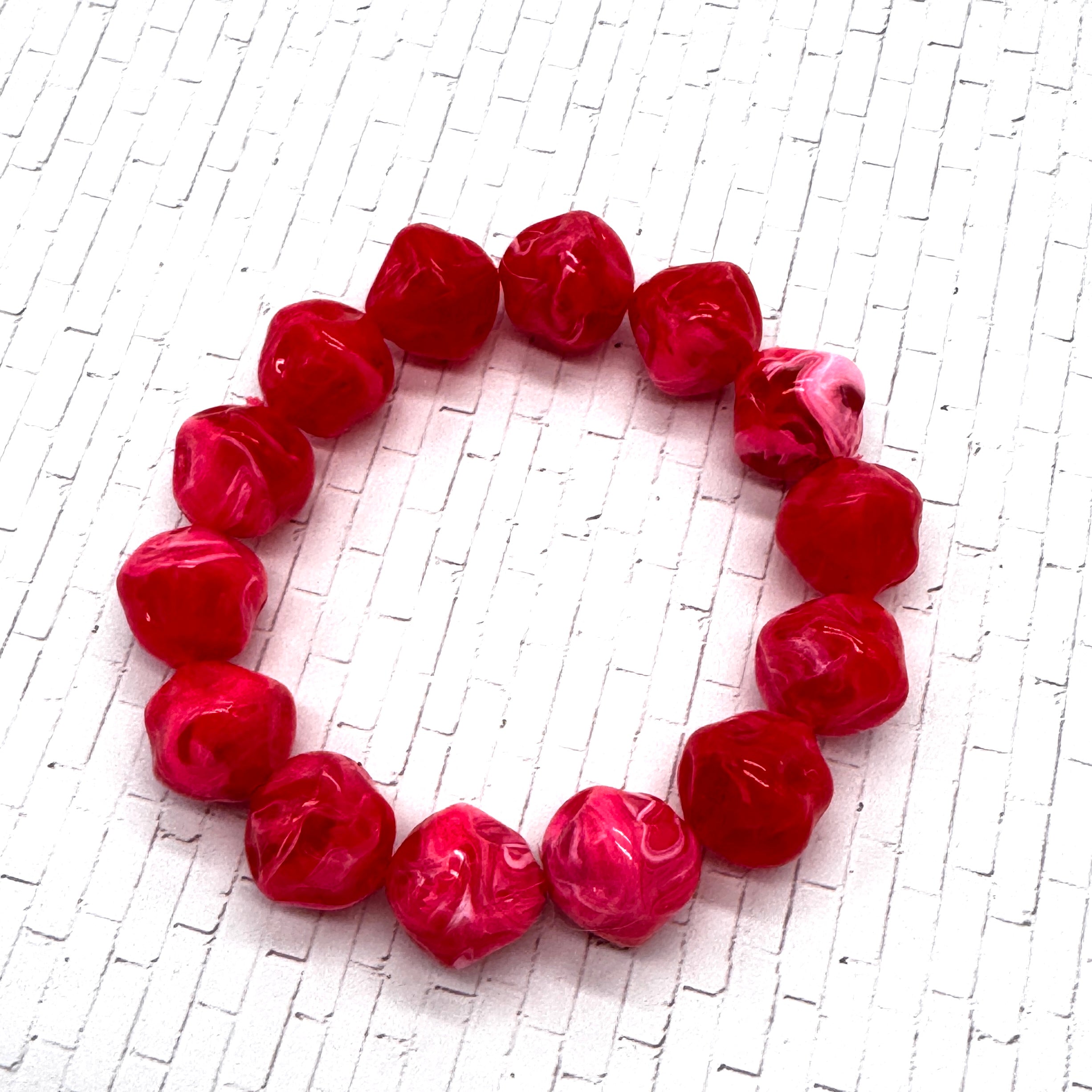 Red marbled bracelet on a textured white background