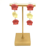 coral and yellow seashell style earrings on a gold stand