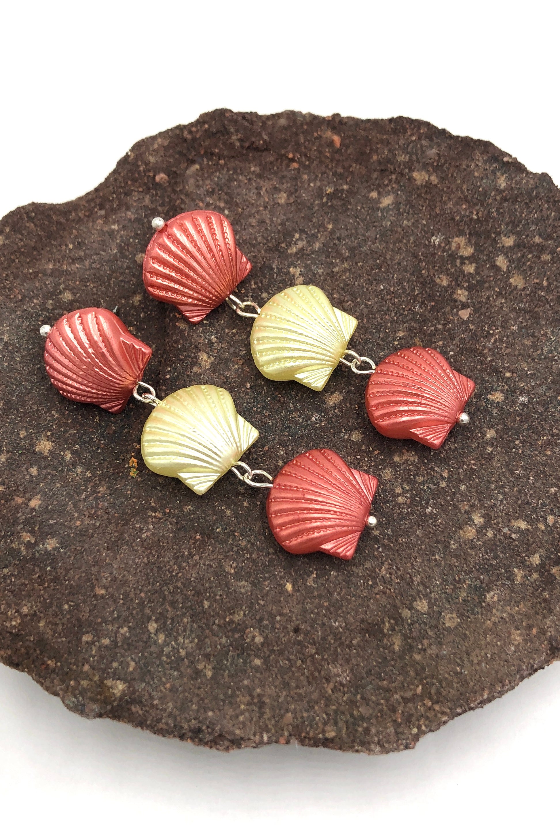 seashell style earrigns laying on a rock