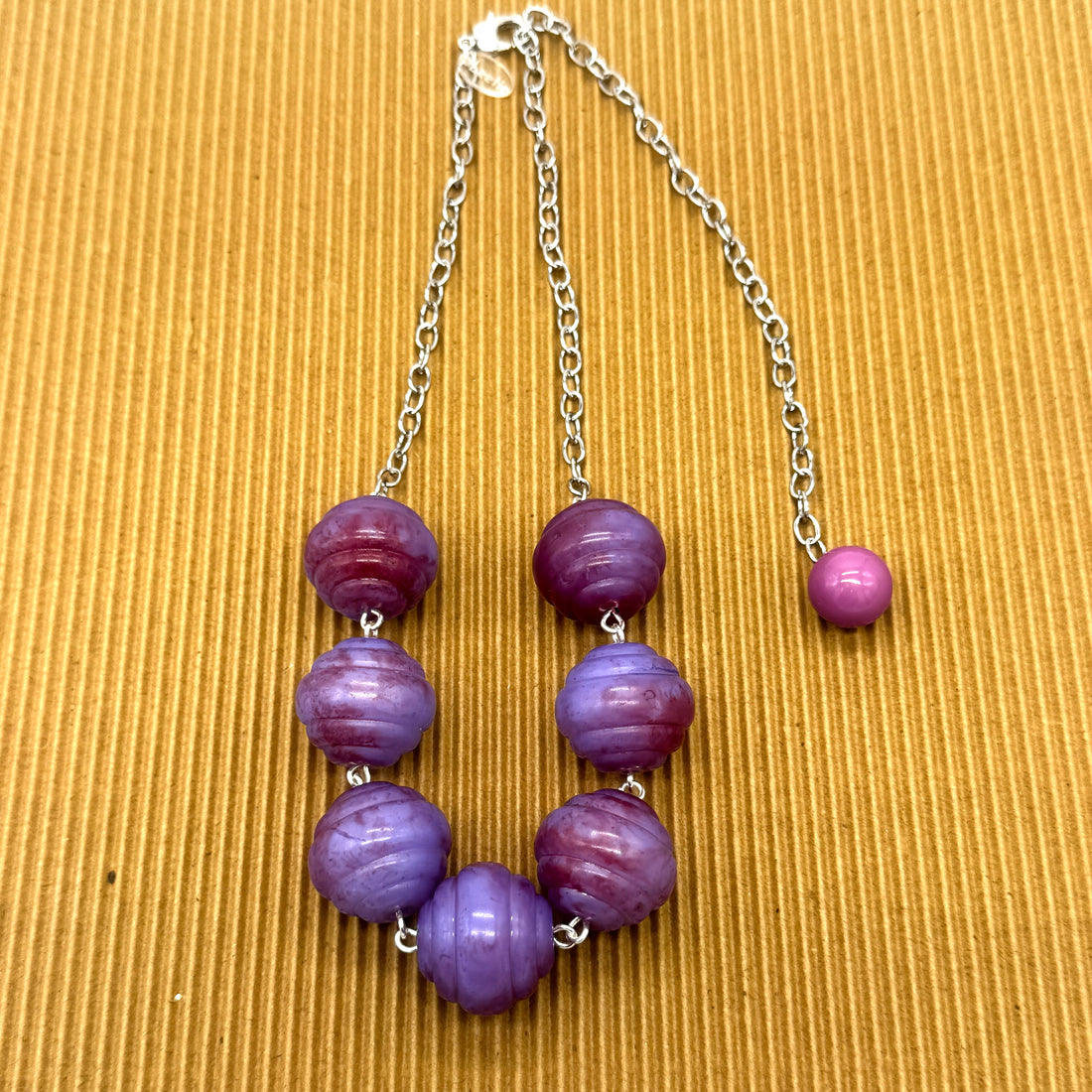 Beaded necklace with purple beads on a textured brown background