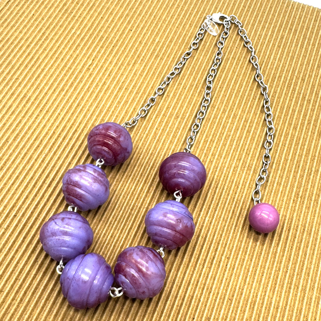Necklace with purple beads on a textured beige background
