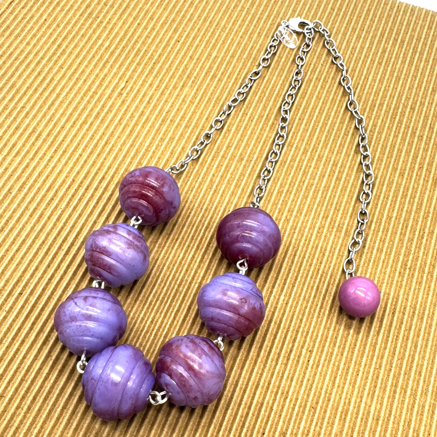 Necklace with purple beads on a textured beige background