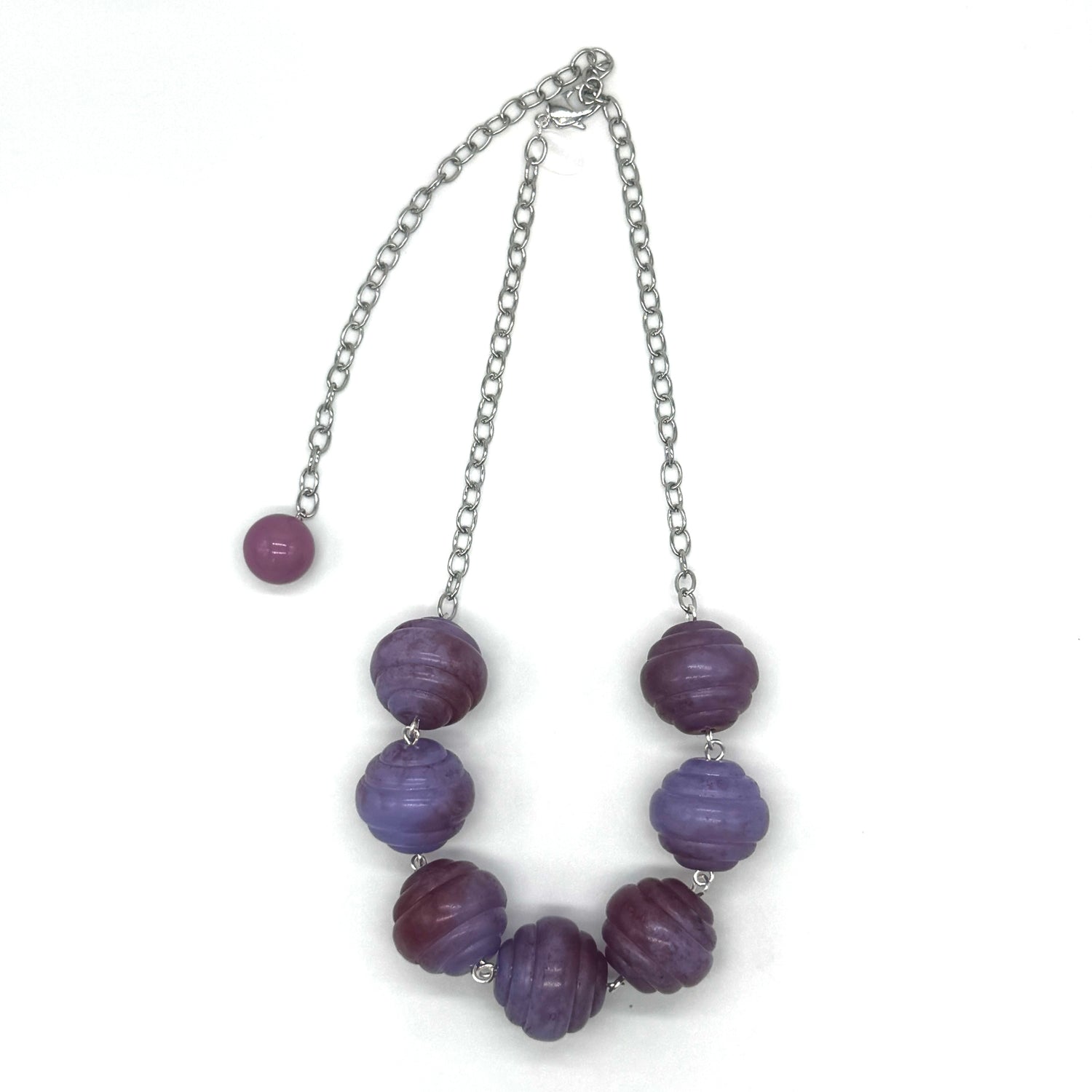 Necklace with purple beads and a silver chain on a white background