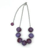 Necklace with purple beads and a silver chain on a white background