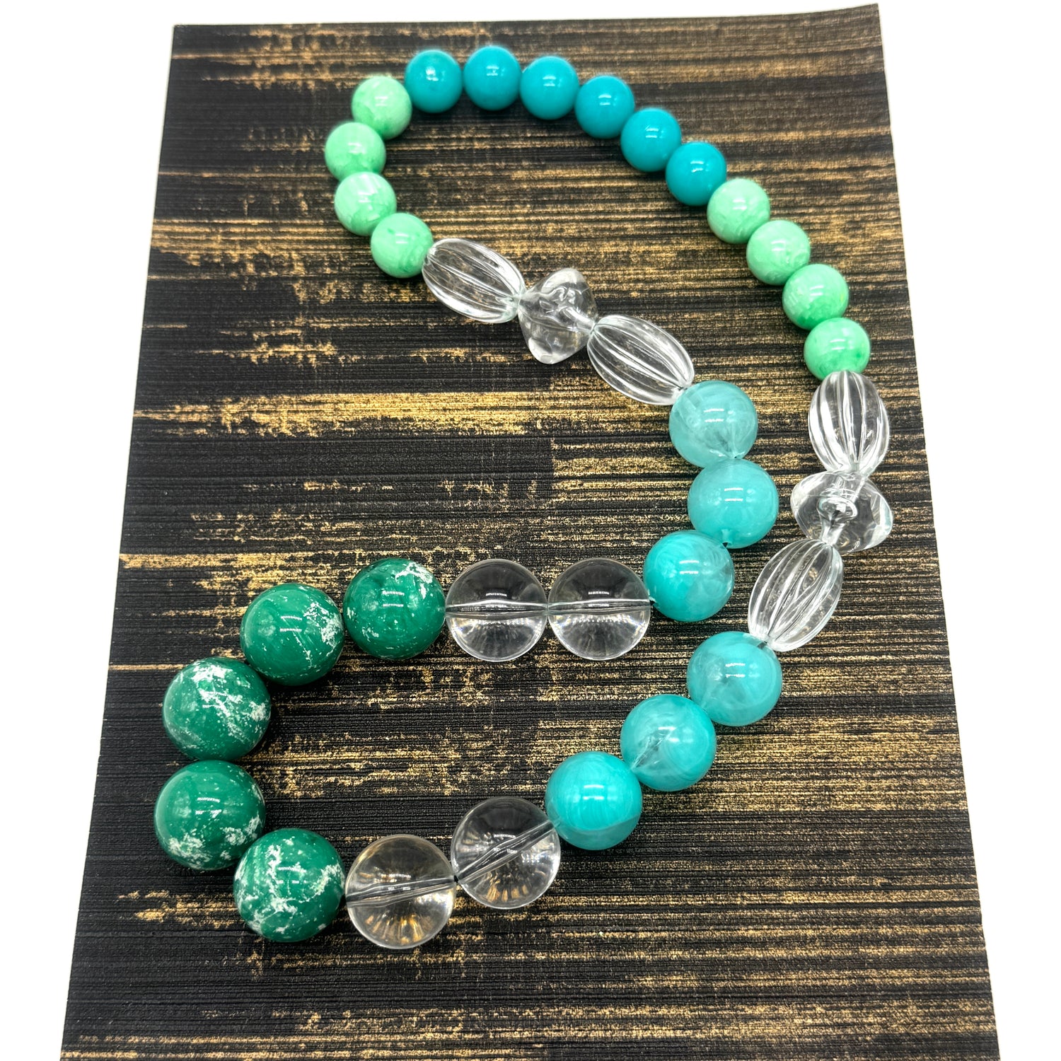 Turquoise and clear beaded neckace on a textured black and gold surface