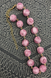 pink beaded necklace on grey background