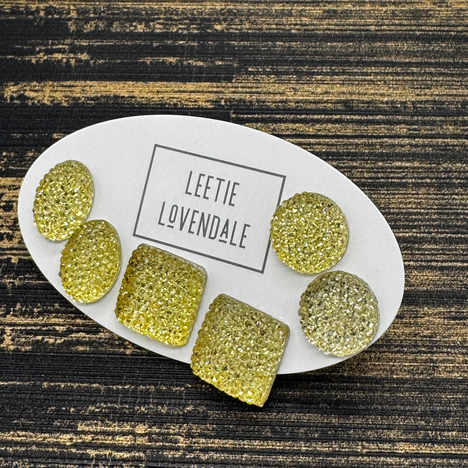 Yellow textured stud earrings on a white card with Leetie Lovendale branding on a white background.