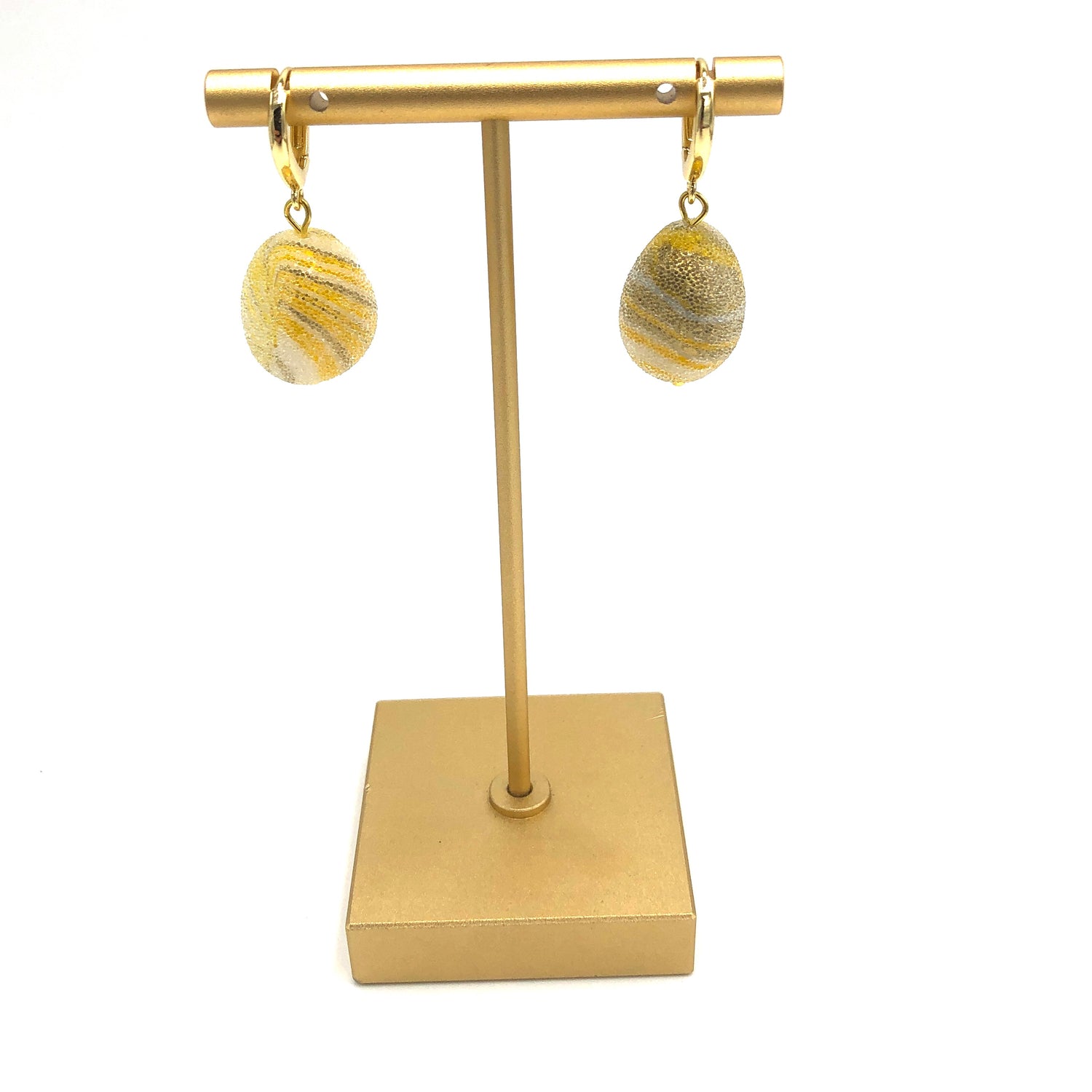 yellow and gold swirl drop earrings on gold stand
