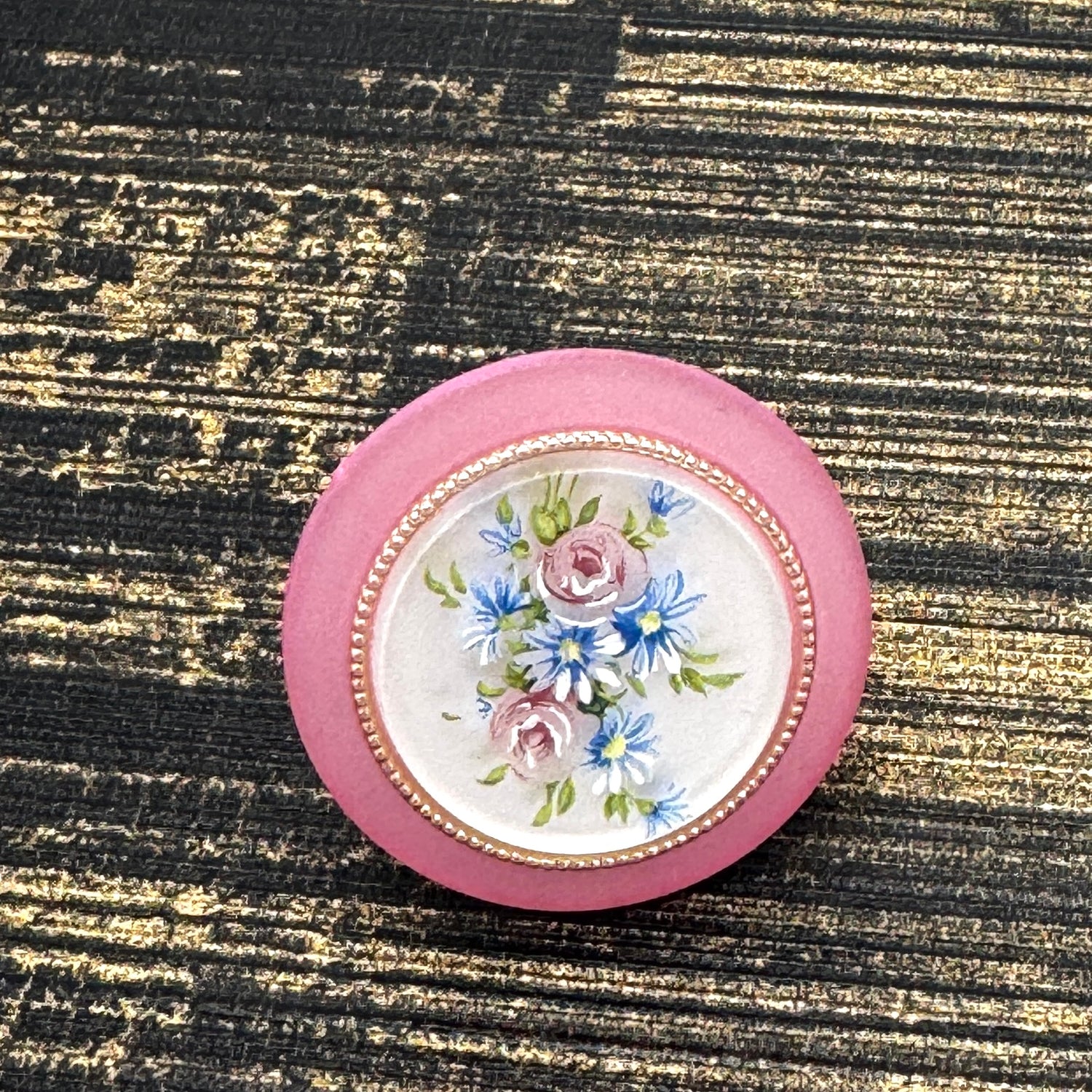 Circular cocktail ring with floral design on a textured black and gold background