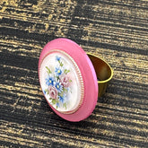 Circular cocktail ring with floral design on a textured black and gold background