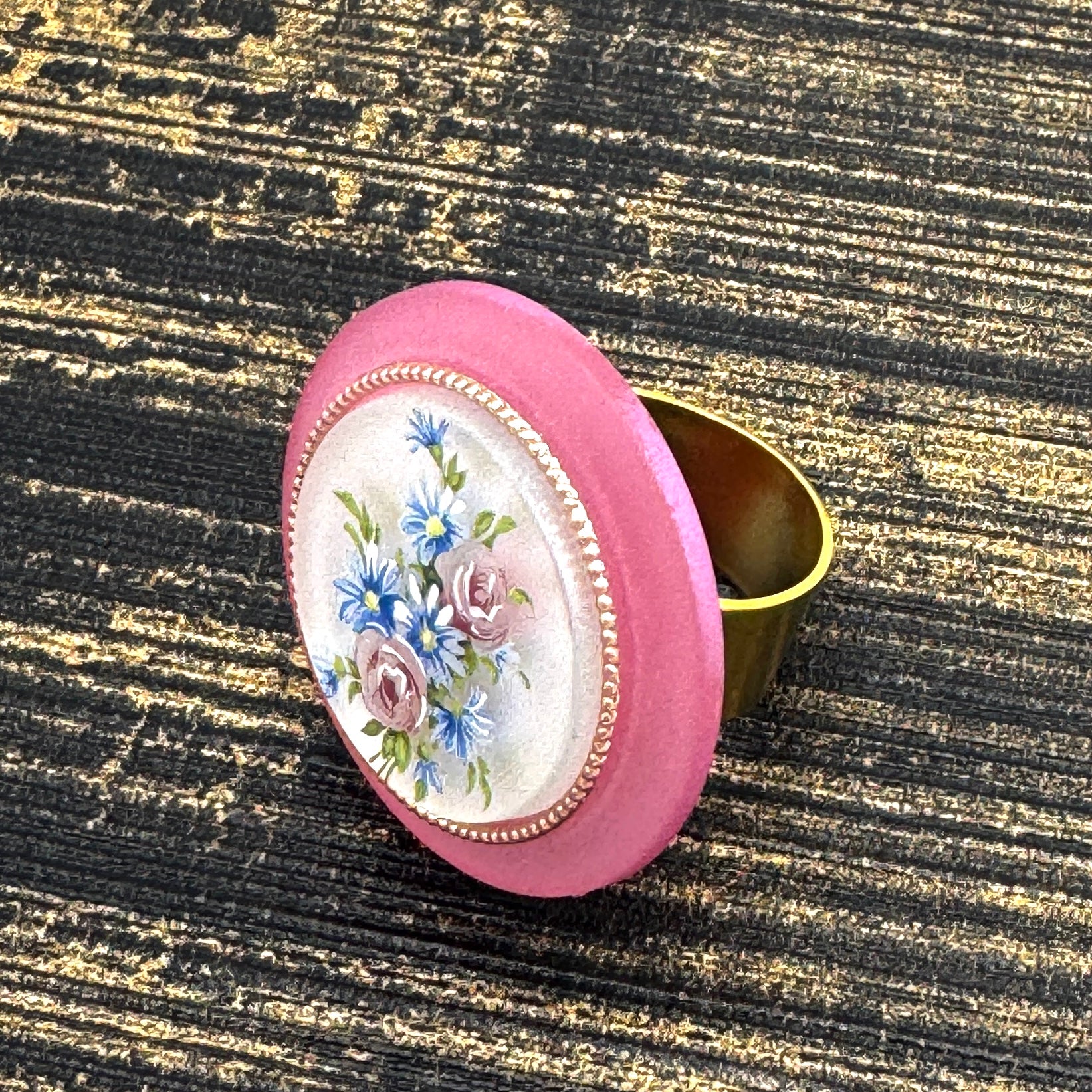 Circular cocktail ring with floral design on a textured black and gold background