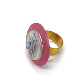 Ring with floral design with pink border and gold band against a white background