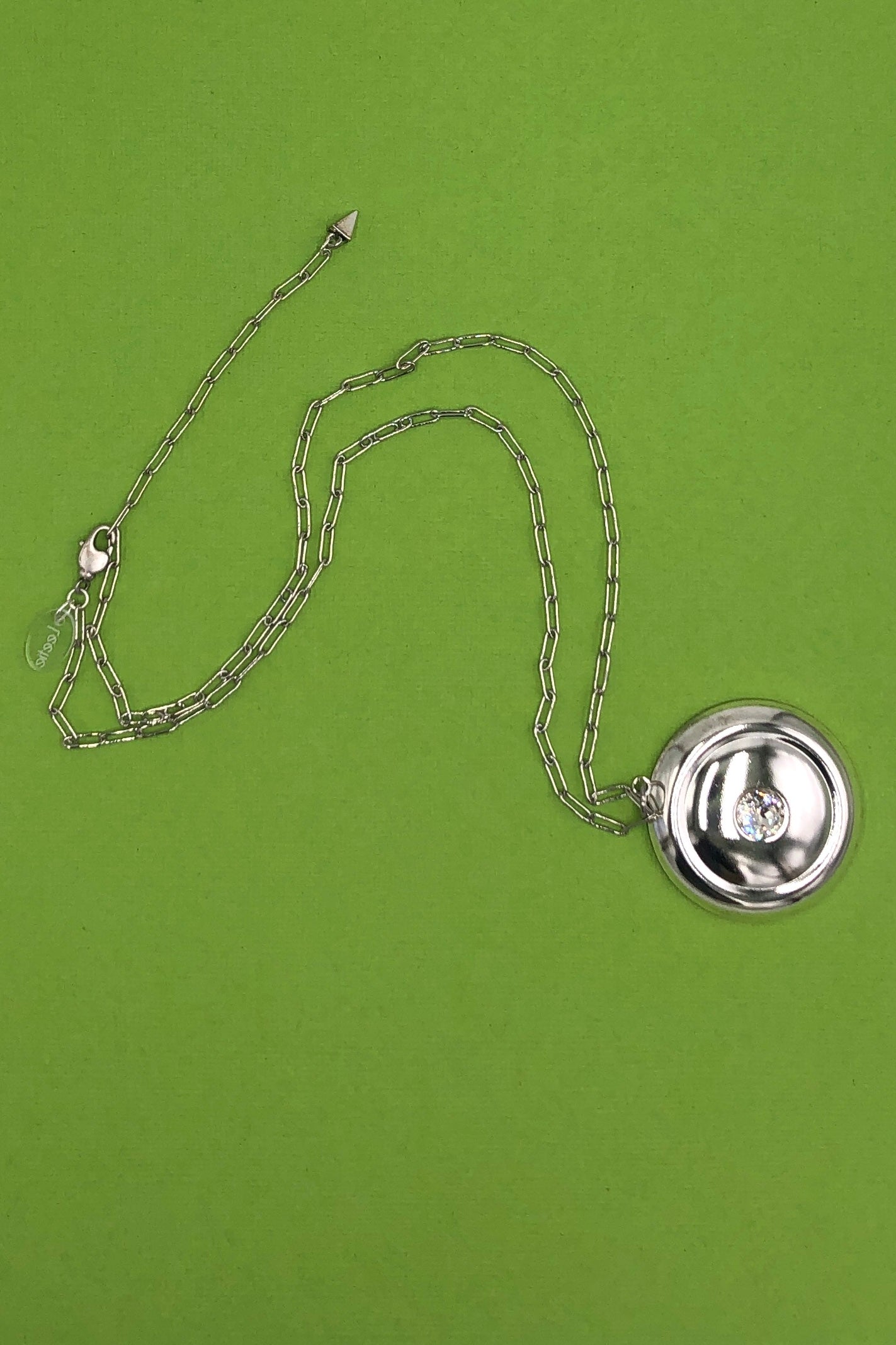 silver paperclip chain necklace with pendant on green background