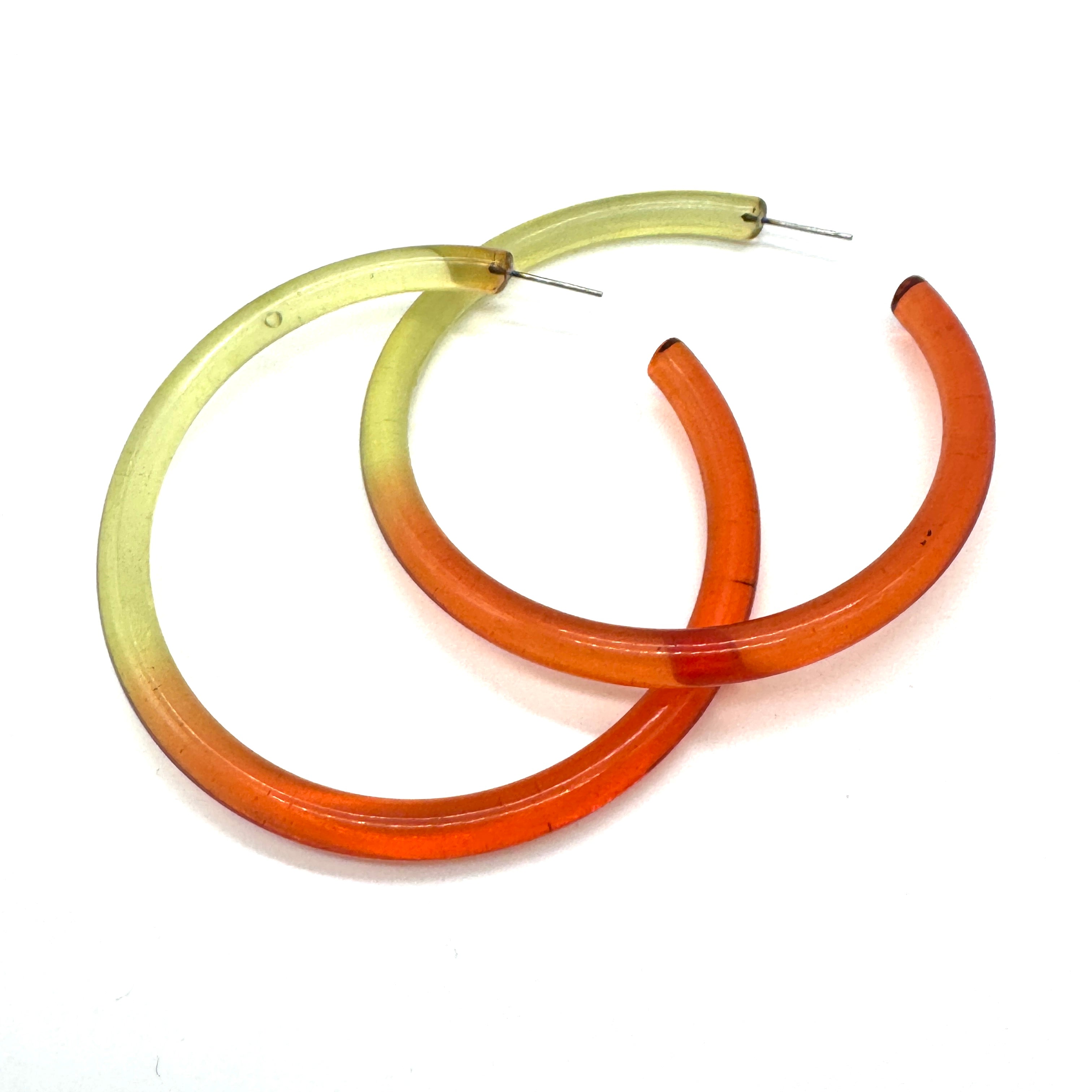 Gradient hoop earrings transitioning from green to cherry red on a white background