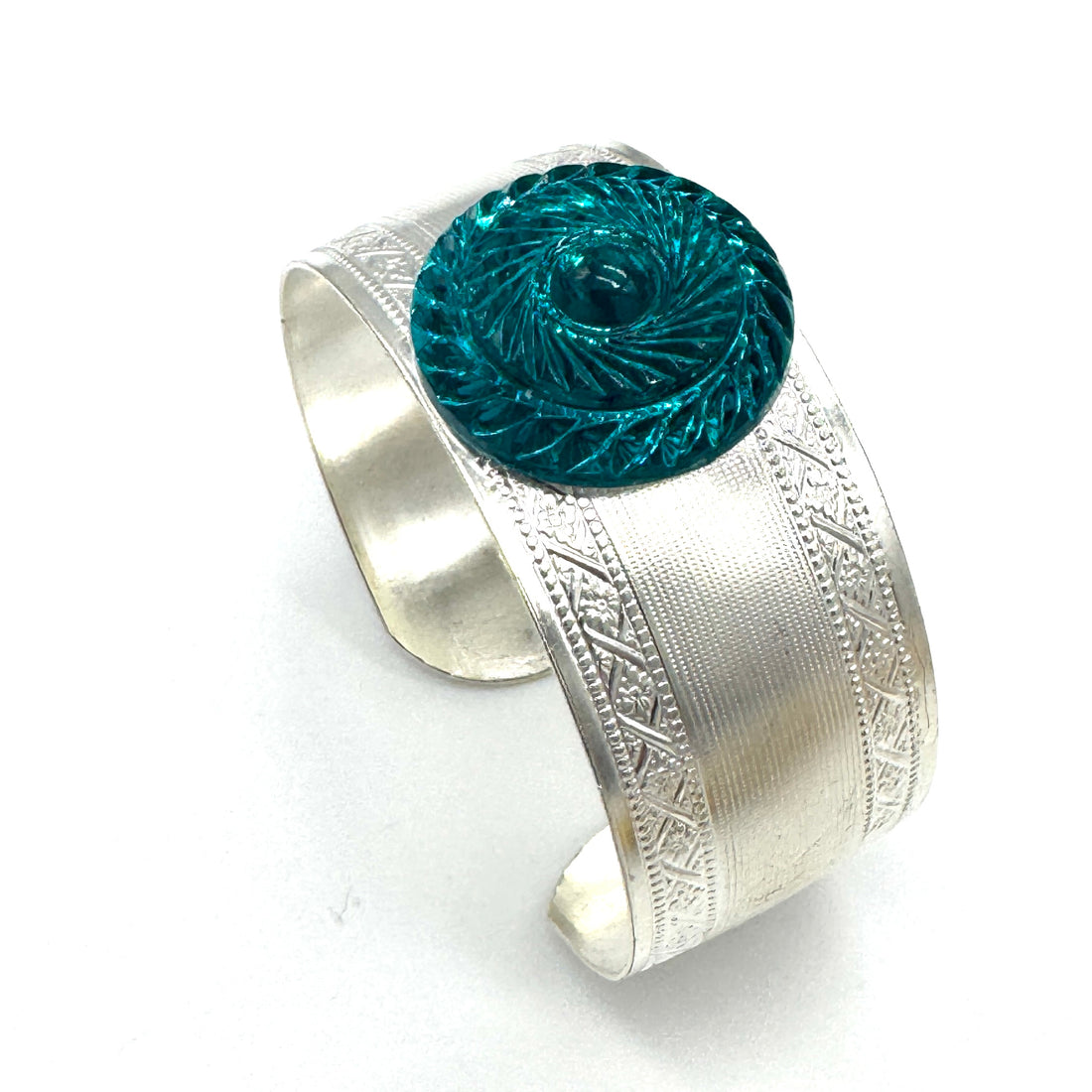 Silver cuff bracelet with a blue decorative lucite cabochon on a white background