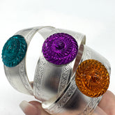 Silver bracelets with colorful circular stones held by a hand on a white background