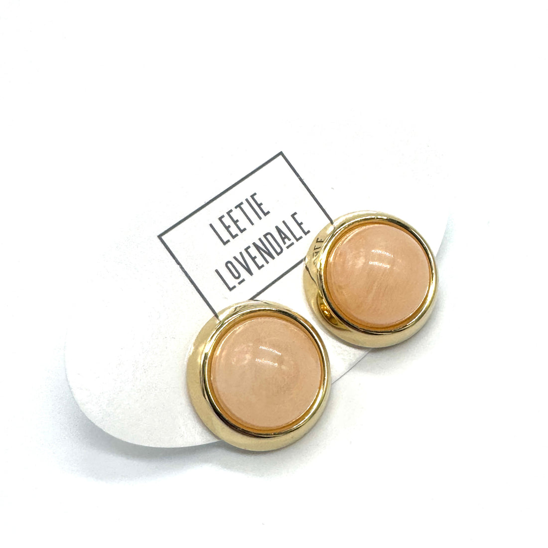 Peach and gold stud earrings on a white background, featuring the brand &