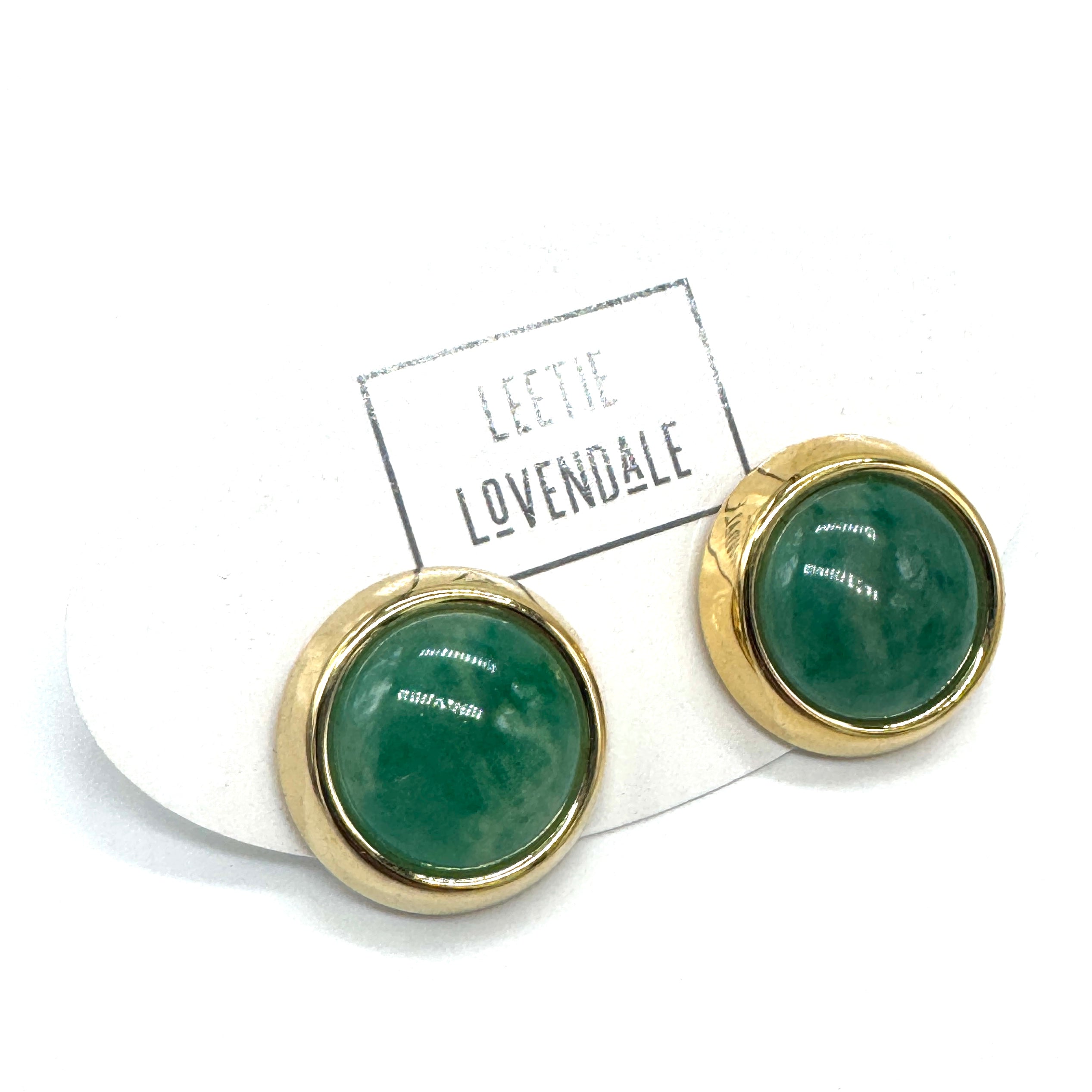 Gold-framed green lucite earrings on a white background with &