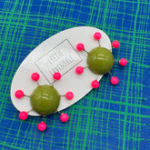OlIve green earrings with hot pink beads radiating from center with posts on a blue and green plaid background.