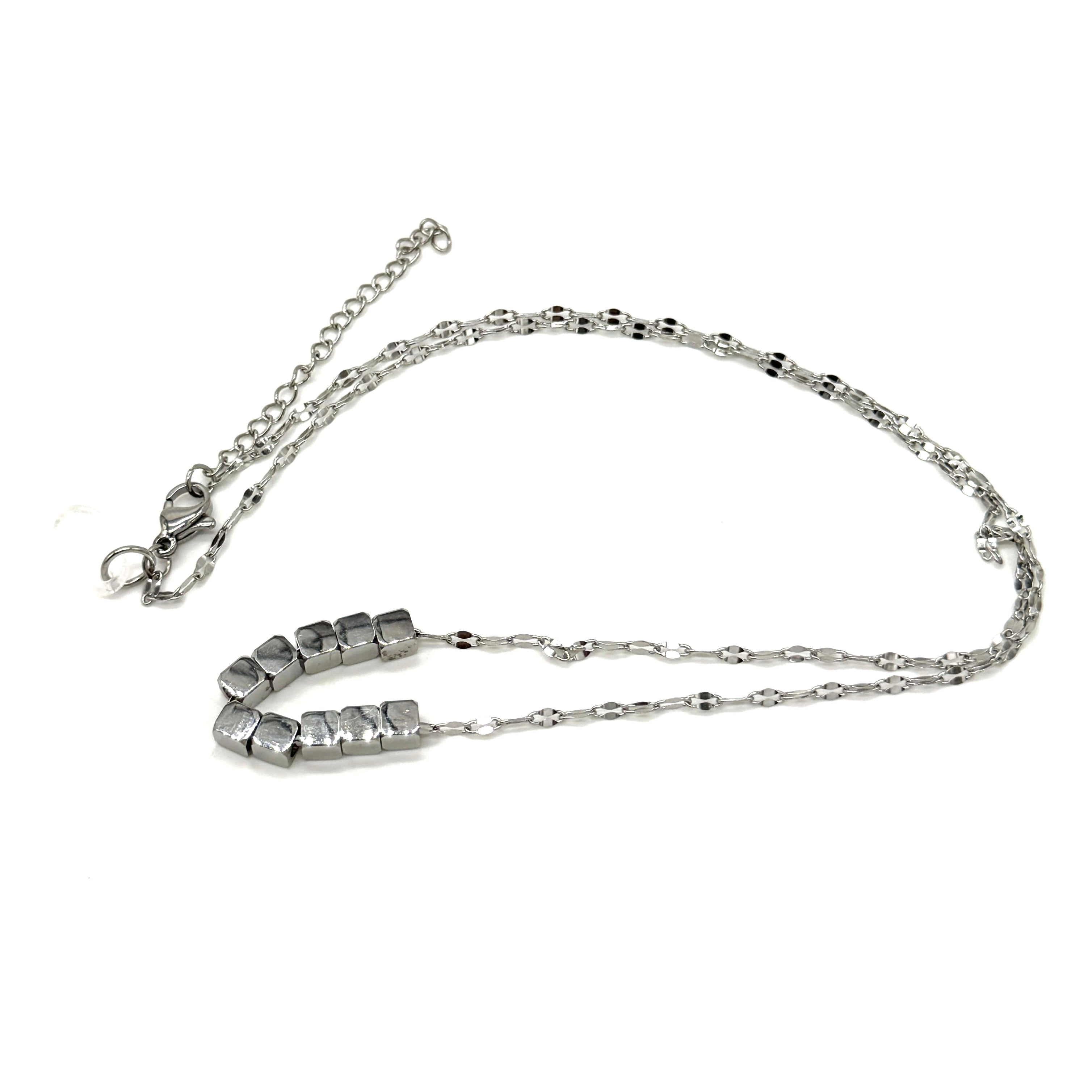 A silver necklace on a white background. It is a fine chain with several cube beads at the center.