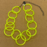 Adjustable necklace featuring large lucite chain links in a neon yellow on a brown background.