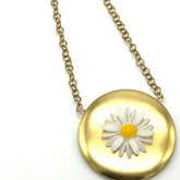 Gold tone medallion necklace with a white daisy at the center.