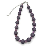 Adjustable necklace featuring dark gray and lilac lucite beads laid on a white background.