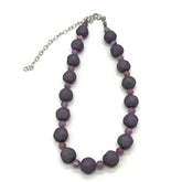 Adjustable necklace featuring dark gray and lilac lucite beads laid on a white background.