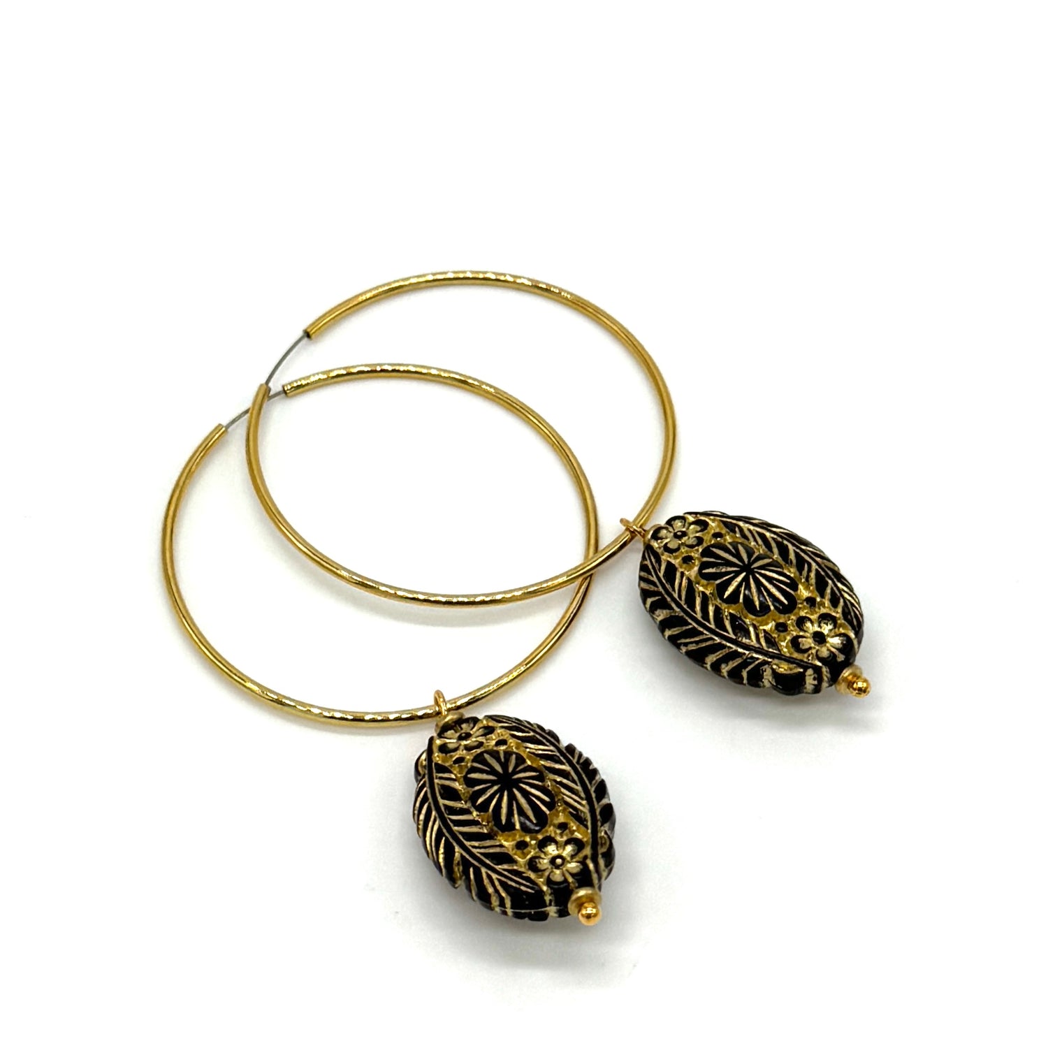 Hoop earrings with carved black bead dangles with gold leaf.