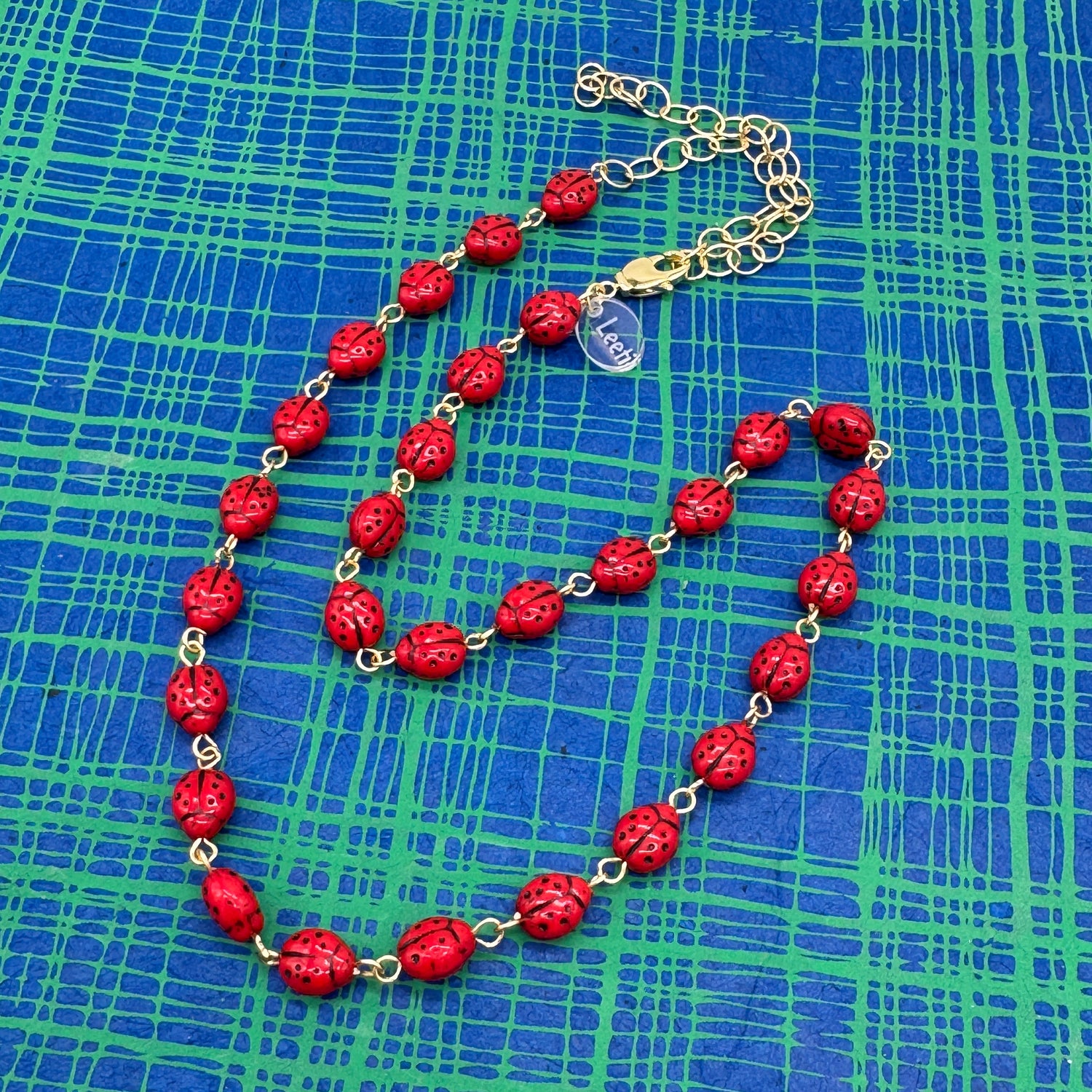 Red necklace with gold chain on a blue checkered background