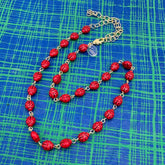 Red necklace with gold chain on a blue checkered background