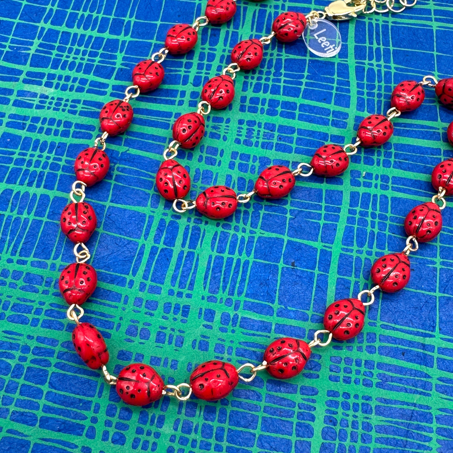 Necklace with red ladybug beads on a blue grid background